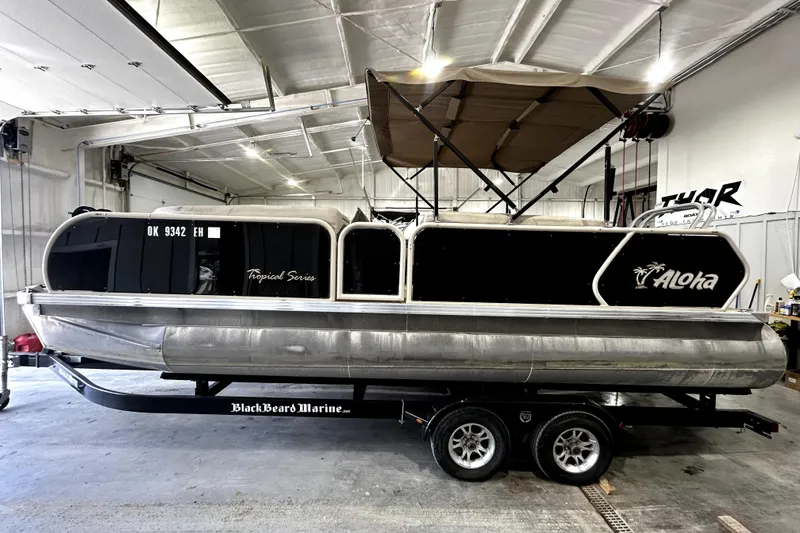 The Image of 2021 Aloha Pontoon Tropical Series boat on trailer in indoor storage. - 0