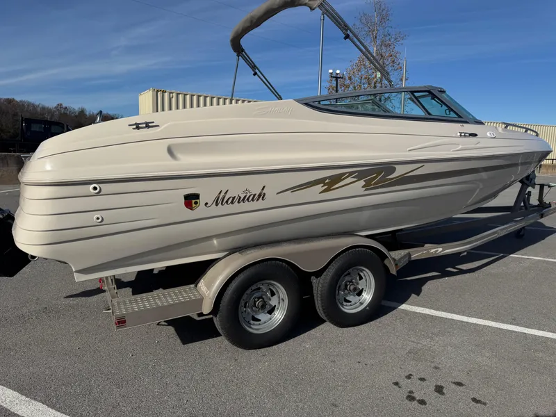 Slide: The Image of 1998 Mariah 222 Shabah boat on trailer, parked in a lot under clear skies. - 3