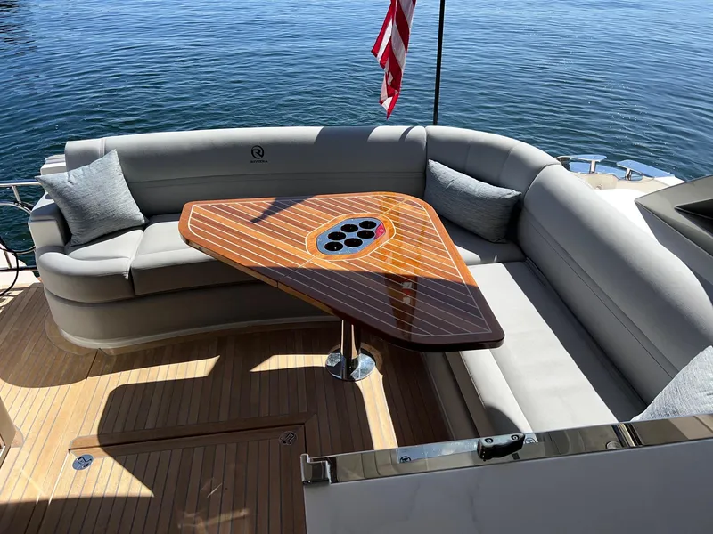Slide: The Image of Luxurious seating area on 2023 Riviera 4600 Sport Yacht Platinum Edition, featuring elegant wood table. - 2
