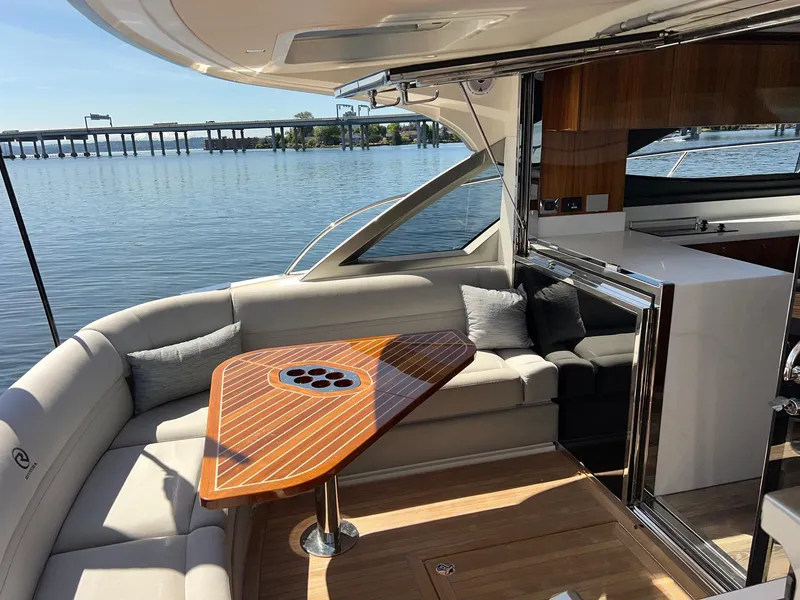 Slide: The Image of 2023 Riviera 4600 Sport Yacht Platinum Edition interior with elegant seating and wooden table. - 21