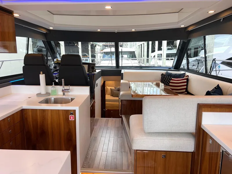 Slide: The Image of 2023 Riviera 4600 Sport Yacht Platinum Edition interior with modern kitchen and seating area. - 3