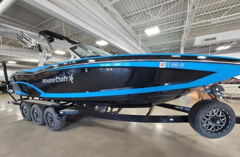 Slide: The Image of 2018 MasterCraft X26 boat with blue and black design on a trailer in a showroom. - 16