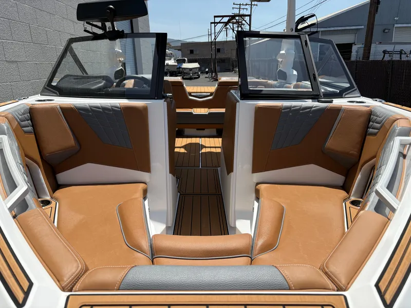 Slide: The Image of 2025 Nautique Super Air Nautique S21 interior with tan and gray seating, open bow design. - 12