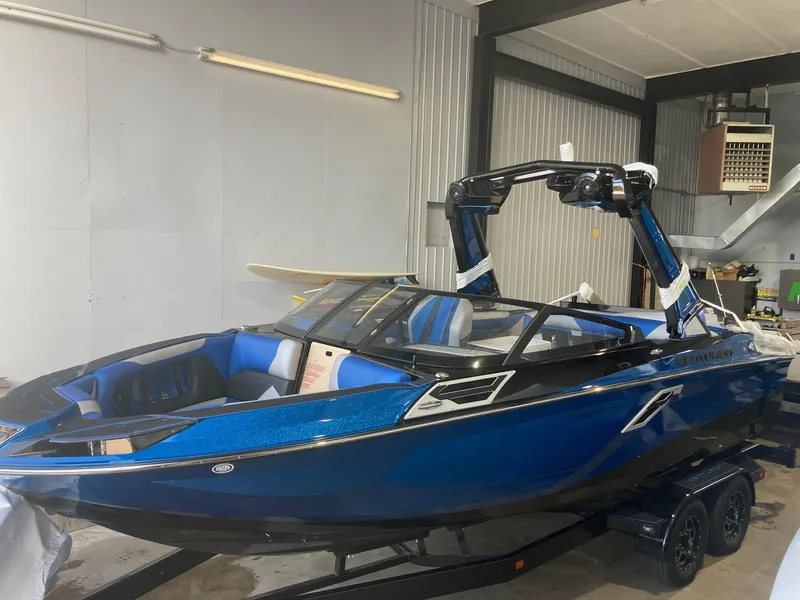 Slide: The Image of 2023 Centurion Ri230 boat in a garage, blue exterior, black trailer. - 1