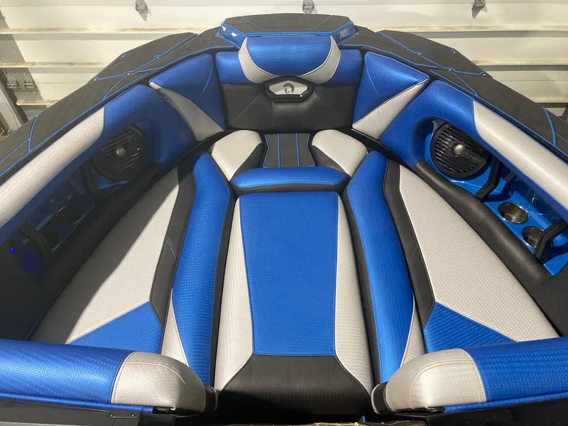 Slide: The Image of 2023 Centurion Ri230 boat interior with blue and gray seating, featuring built-in speakers. - 2