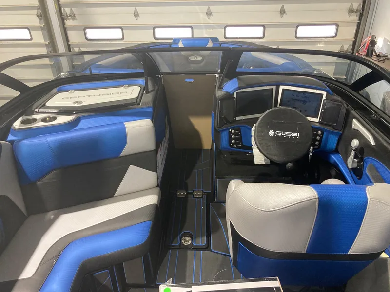 Slide: The Image of 2023 Centurion Ri230 boat interior with blue and gray seating, modern dashboard, and steering wheel. - 3