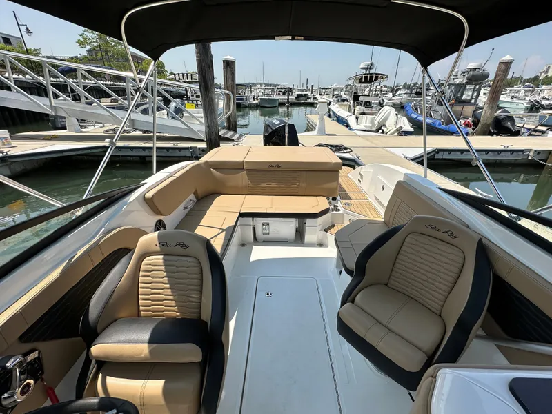 Slide: The Image of 2023 Sea Ray SPX 230 OB boat interior at marina, featuring tan seating and sleek design. - 5
