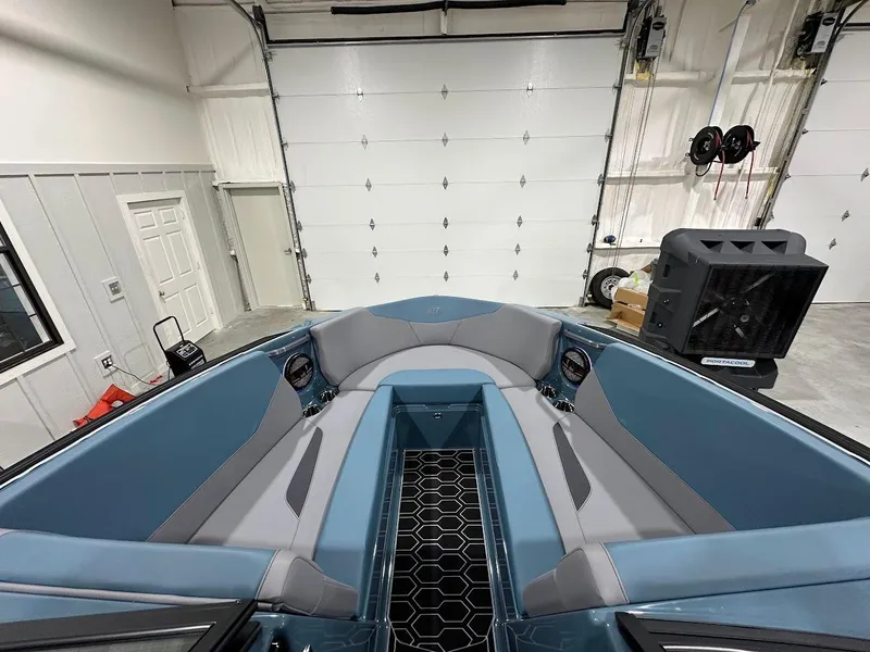 Slide: The Image of 2025 MasterCraft NXT23 boat interior with blue and gray seating in a garage. - 12