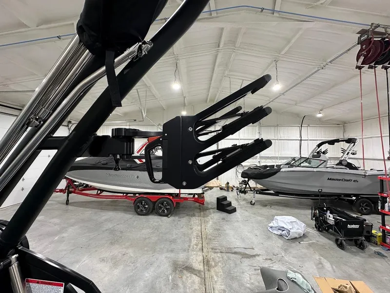 Slide: The Image of 2025 MasterCraft NXT23 boats in a garage, featuring a wakeboard rack in the foreground. - 15