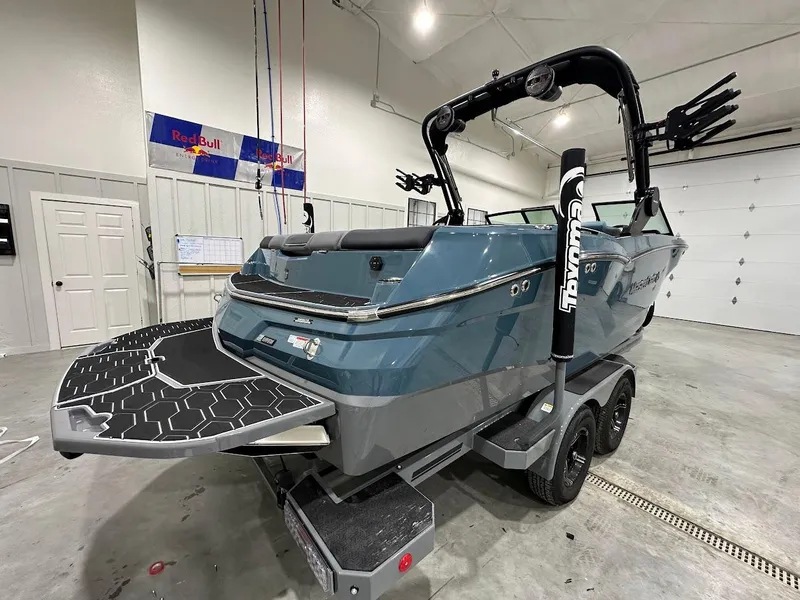 Slide: The Image of 2025 MasterCraft NXT23 boat in garage, featuring sleek design and dual-axle trailer. - 3