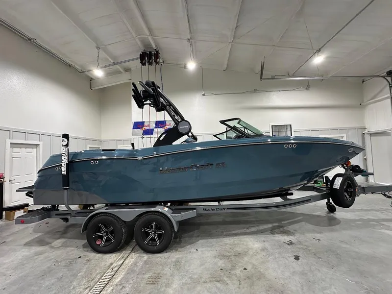 Slide: The Image of 2025 MasterCraft NXT23 boat in a showroom, side view on a trailer. - 4