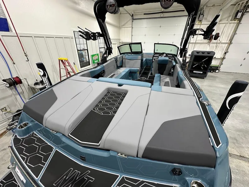 Slide: The Image of 2025 MasterCraft NXT23 boat interior in a garage, featuring sleek seating and modern design. - 7