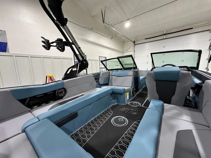 Slide: The Image of 2025 MasterCraft NXT23 boat interior with blue and gray seating in a garage setting. - 9