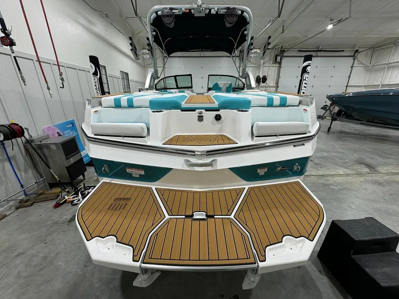 Slide: The Image of 2025 MasterCraft XT23 boat in a garage, featuring a teak swim platform and turquoise accents. - 14