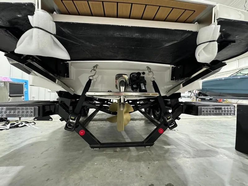 Slide: The Image of 2025 MasterCraft XT23 boat underside showing propeller and wakeboard tower in a garage. - 15