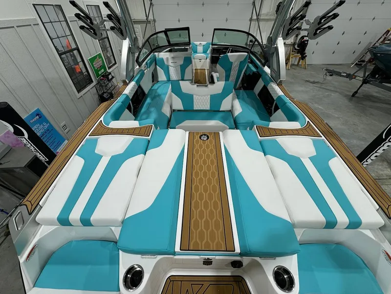 Slide: The Image of 2025 MasterCraft XT23 boat interior with turquoise and white seating in a garage setting. - 19