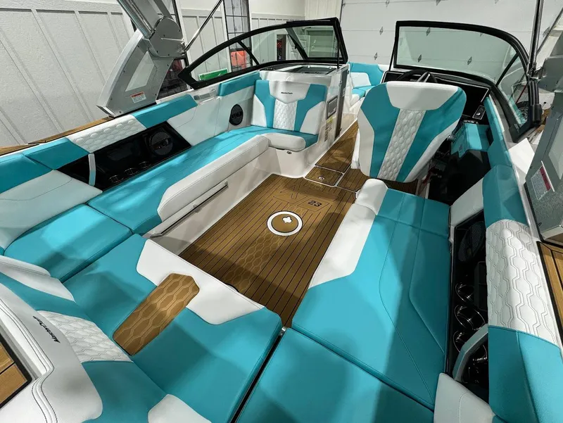 Slide: The Image of 2025 MasterCraft XT23 boat interior with turquoise and white seating, wood flooring. - 20