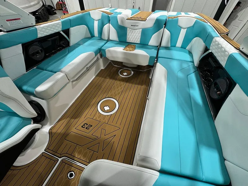 Slide: The Image of 2025 MasterCraft XT23 boat interior with turquoise and white seating, teak flooring. - 22