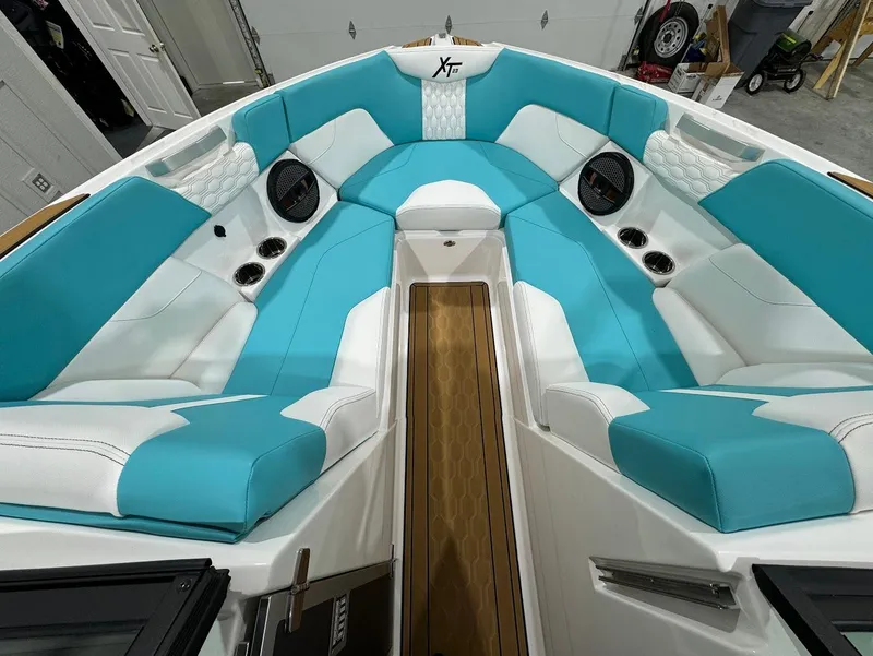 Slide: The Image of 2025 MasterCraft XT23 boat interior with turquoise and white seating, featuring speakers and cup holders. - 23