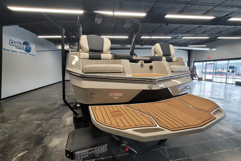 Slide: The Image of 2025 MasterCraft XT22 T boat displayed in showroom with teak deck and cushioned seating. - 20