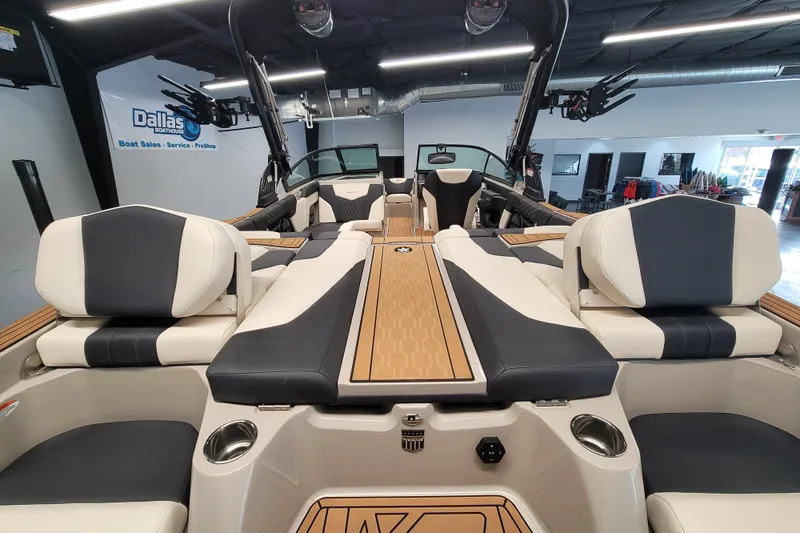 Slide: The Image of 2025 MasterCraft XT22 T boat interior with sleek seating and modern design in showroom. - 23