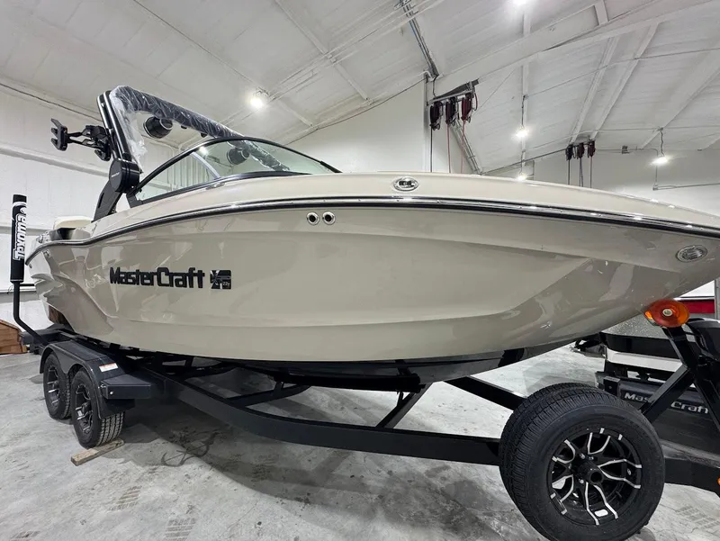 Slide: The Image of 2025 MasterCraft XT22 T boat on trailer in showroom, side view. - 7