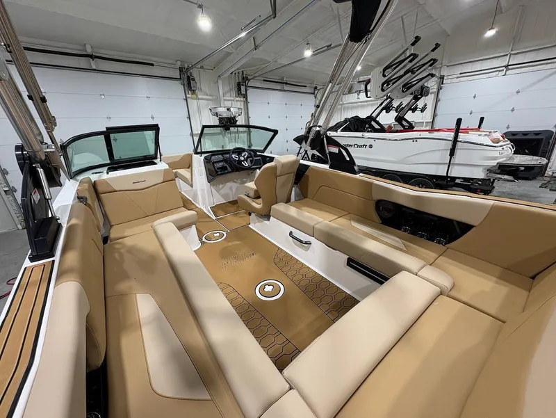 Slide: The Image of 2025 MasterCraft NXT24 boat interior with tan seating, in a spacious garage setting. - 10