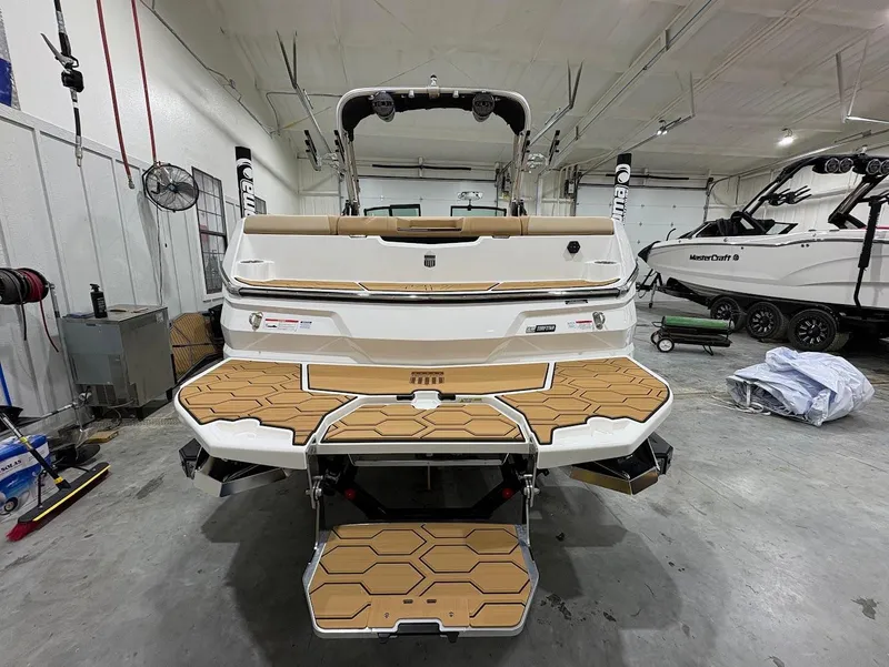 Slide: The Image of 2025 MasterCraft NXT24 boat in showroom, featuring teak-style swim platform and modern design. - 7