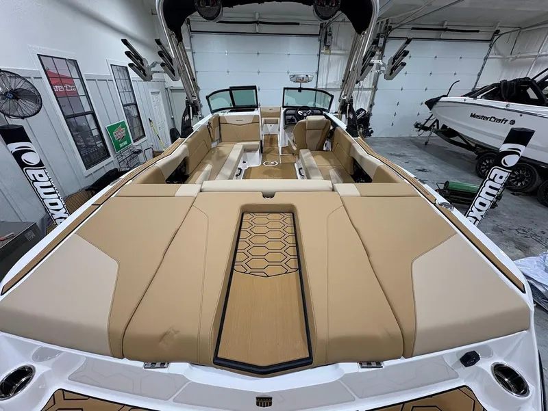 Slide: The Image of 2025 MasterCraft NXT24 boat interior with tan seating and modern design in a garage setting. - 8