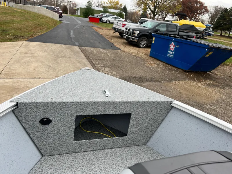 Slide: The Image of 2025 Lund 1600 Fury Tiller boat parked near a driveway with vehicles and a dumpster. - 11