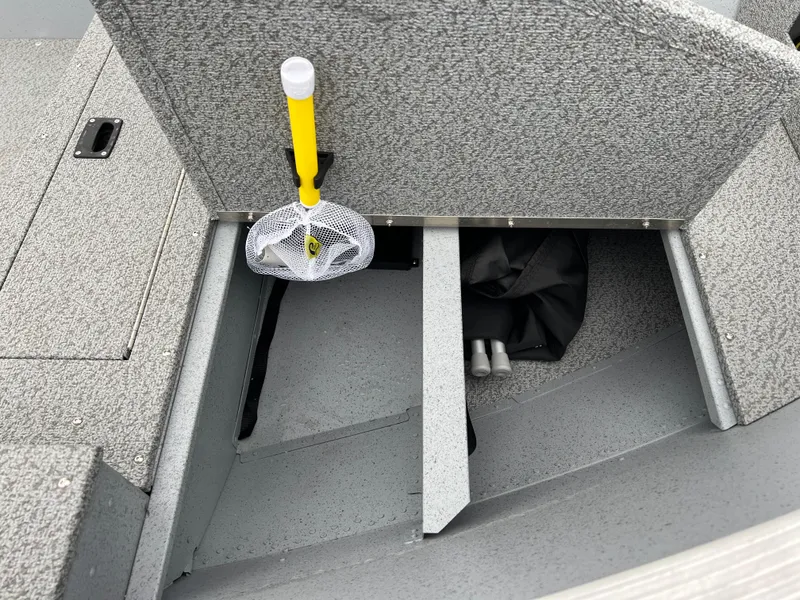 Slide: The Image of 2025 Lund 1600 Fury Tiller boat storage compartment with a yellow-handled net. - 12