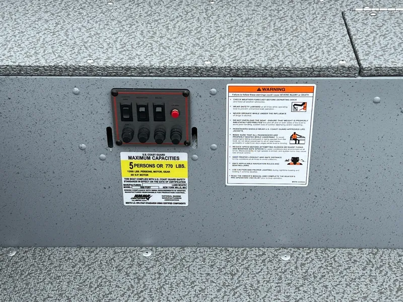 Slide: The Image of Control panel and warning labels on a 2025 Lund 1600 Fury Tiller boat. - 14