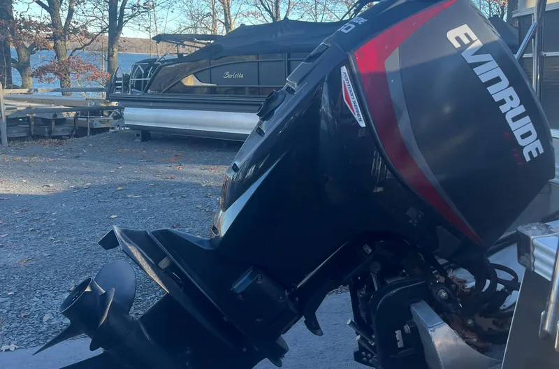 Slide: The Image of 2015 Manitou 25 Oasis SR with Evinrude outboard motor in a boatyard setting. - 11