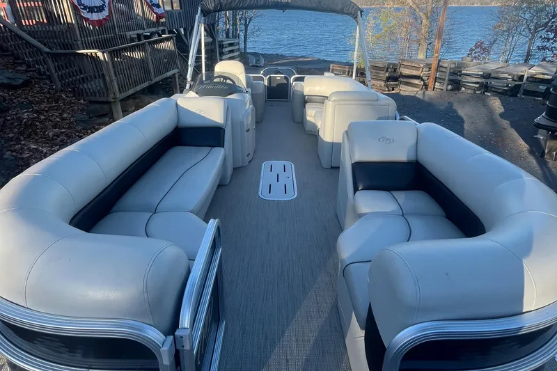 Slide: The Image of 2015 Manitou 25 Oasis SR pontoon boat with spacious seating, docked by a serene lake. - 2