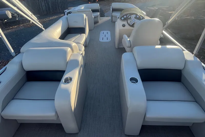 Slide: The Image of 2015 Manitou 25 Oasis SR boat interior with plush seating and steering console. - 5