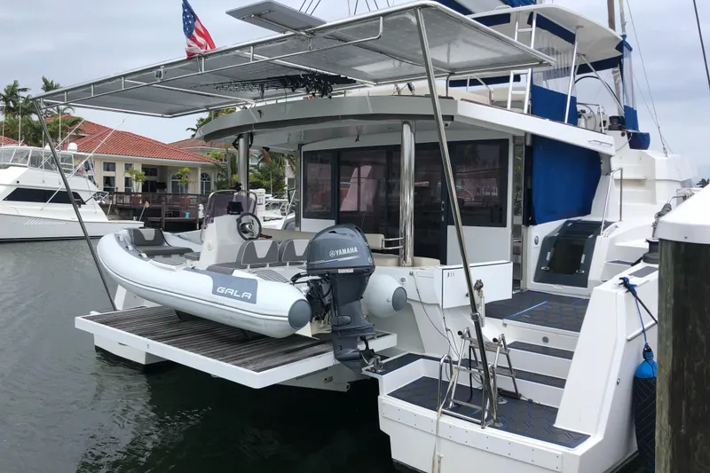 Slide: The Image of Bali 5.4 catamaran docked with inflatable boat, 2021 model, marina setting. - 10