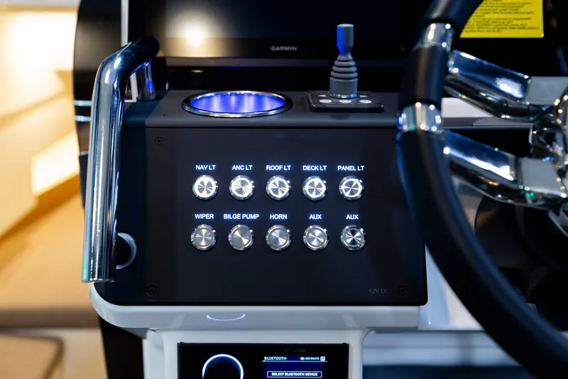Slide: The Image of Control panel of 2024 Quarken 27 T-Top V2 boat with illuminated switches and steering wheel. - 14
