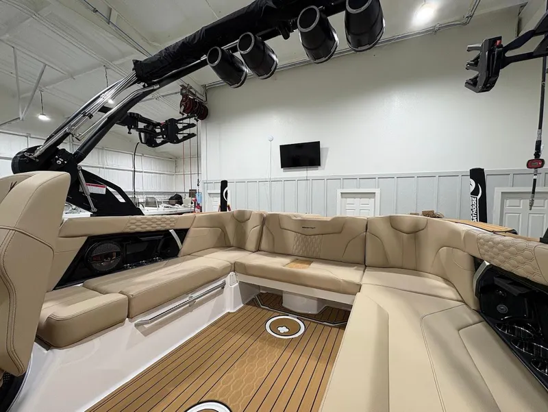 Slide: The Image of 2025 MasterCraft XT22 boat interior with beige seating and teak flooring in a showroom. - 10