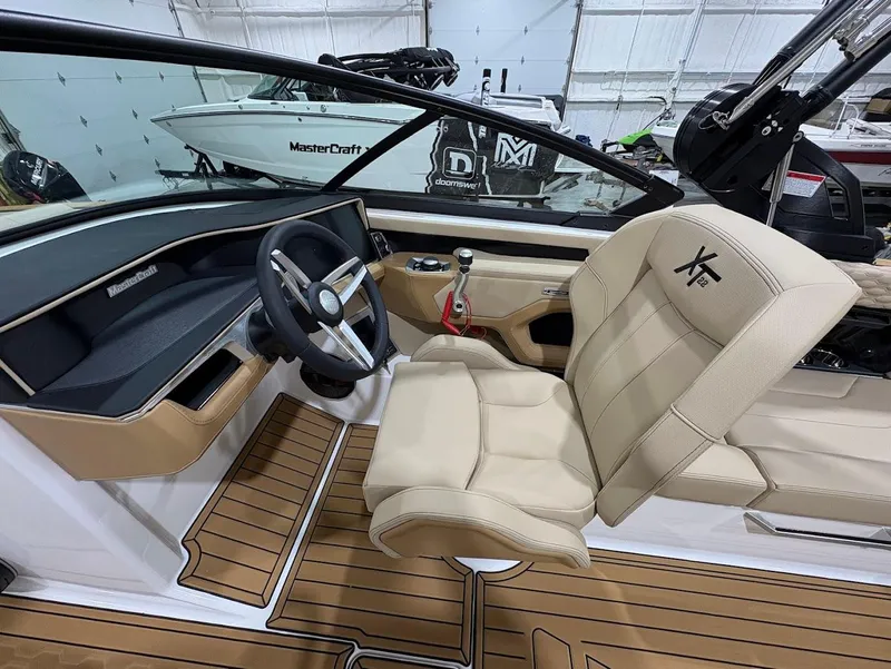 Slide: The Image of 2025 MasterCraft XT22 boat interior with beige seating and sleek dashboard design. - 11