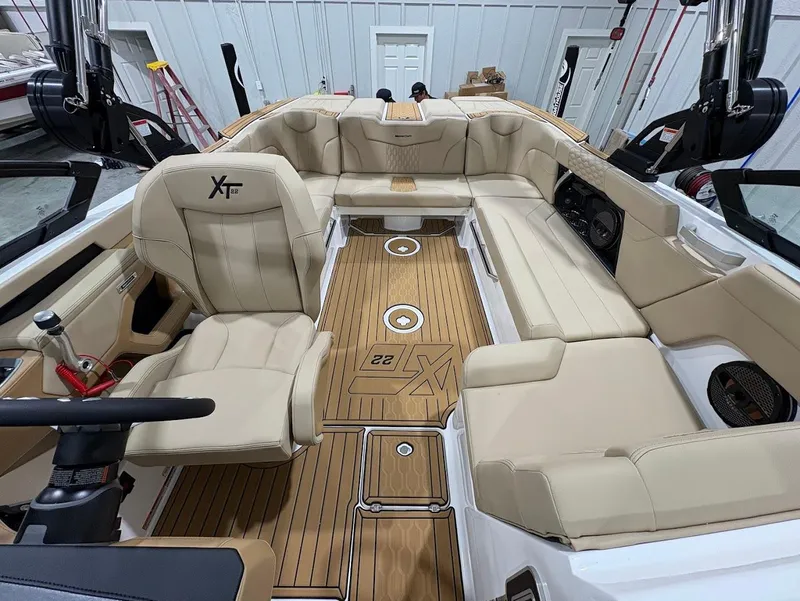 Slide: The Image of 2025 MasterCraft XT22 boat interior with beige seating and wood flooring. - 12