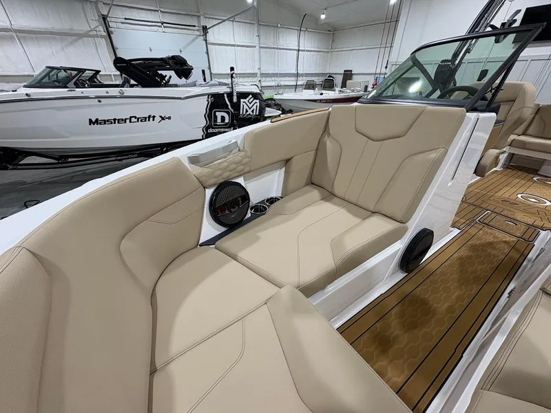 Slide: The Image of 2025 MasterCraft XT22 boat interior with beige seating and wood accents in a showroom. - 13