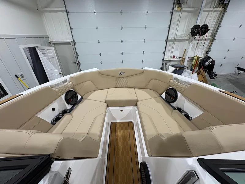 Slide: The Image of 2025 MasterCraft XT22 boat interior with beige seating and wood accents in a garage. - 15