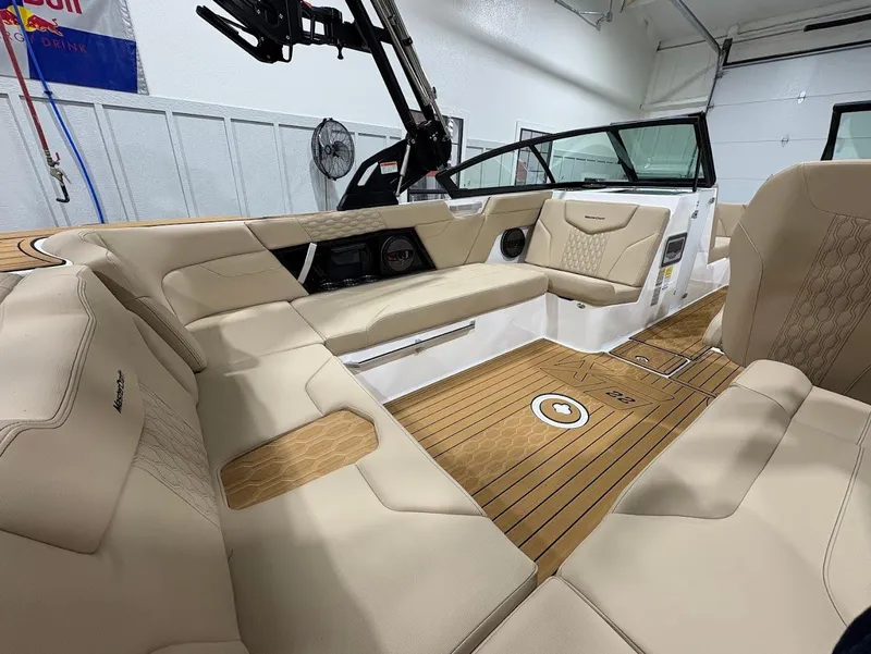 Slide: The Image of 2025 MasterCraft XT22 boat interior with beige seating and teak flooring in a showroom. - 8