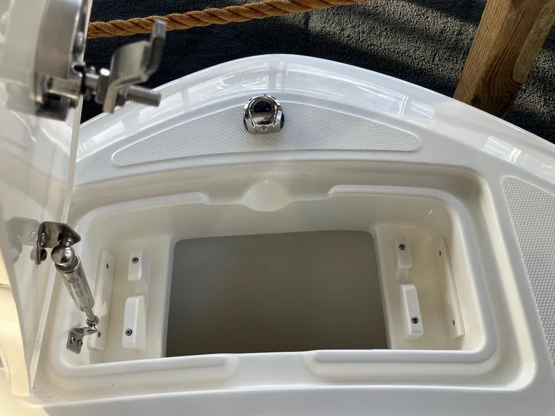 Slide: The Image of Boston Whaler 210 Vantage 2025 storage compartment with open lid and latch mechanism. - 12