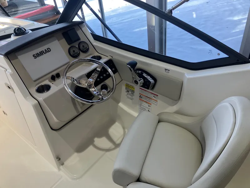 Slide: The Image of 2025 Boston Whaler 210 Vantage boat cockpit with steering wheel and Simrad display. - 9