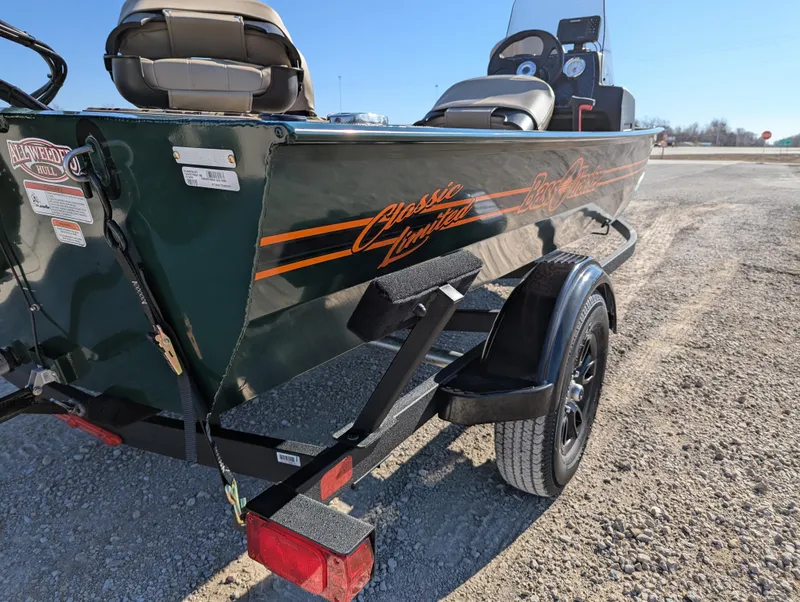Slide: The Image of 2025 Tracker Bass Tracker Classic Limited boat on trailer, green with orange accents, parked outdoors. - 44