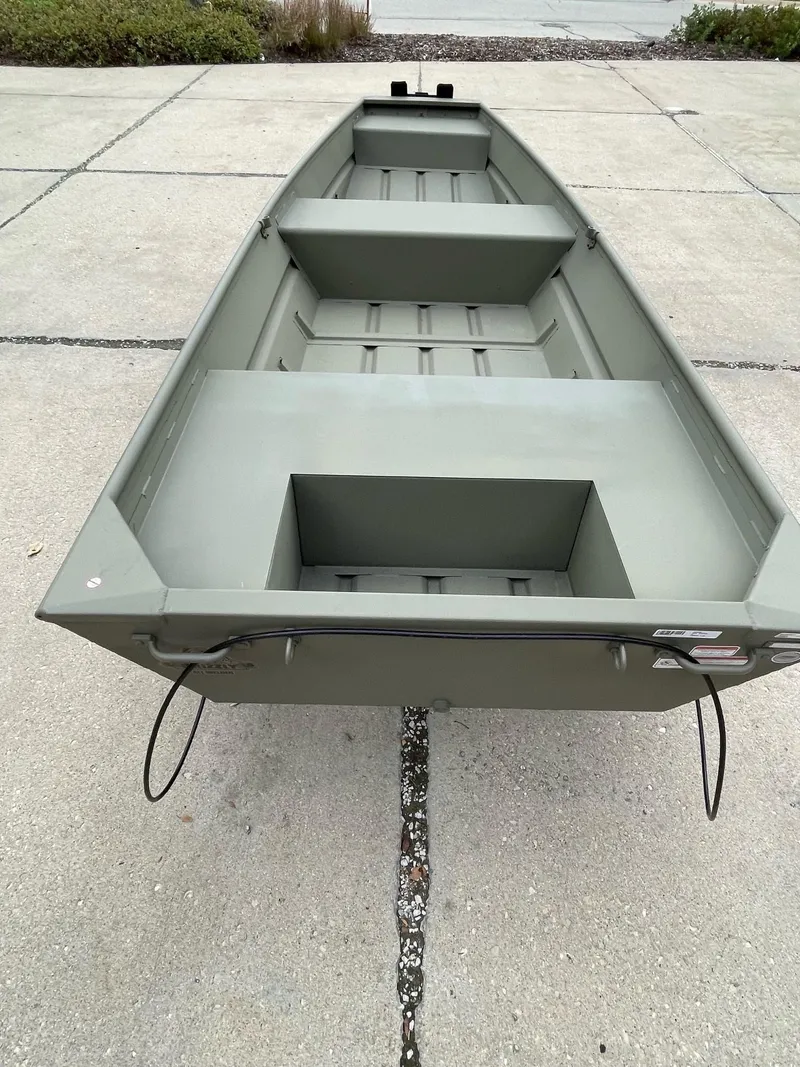Slide: The Image of 2025 Tracker Grizzly 1436 Utility boat on concrete surface, showcasing interior seating and design. - 2