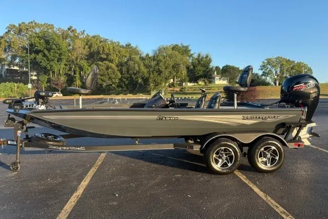 Slide: The Image of 2025 Ranger RT198P fishing boat on trailer in parking lot, surrounded by trees. - 2