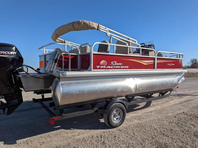 Slide: The Image of 2025 Sun Tracker Bass Buggy 18 DLX pontoon boat on trailer, red and silver design. - 5