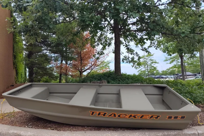 The Image of 2025 Tracker Grizzly 1036 Utility boat displayed outdoors among trees. - 0